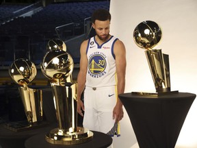 Golden State Warriors' Stephen Curry looks at the 4 Larry O'Brien trophies during Media Day at Chase Center in San Francisco, Sunday, Sept. 25, 2022.