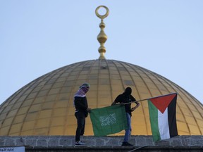 FILE - Masked Palestinians carry Palestinian and Hamas flags during Eid al-Fitr celebrations next to the next to the Dome of the Rock Mosque in the Al-Aqsa Mosque compound in the Old City of Jerusalem, May 2, 2022. The Palestinian militant group Hamas is threatening hostile actions against Israel over what it called "violations against Jerusalem and the Al-Aqsa Mosque" ahead of the upcoming Jewish High Holidays. Hamas' threats on Thursday, Sept. 22, 2022, came just ahead of the Jewish new year on Sunday and a day after a group of Jewish religious extremists visited the contested holy site.