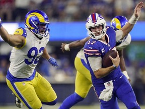 Buffalo Bills quarterback Josh Allen, right, is chased by Los Angeles Rams defensive tackle Jonah Williams (92) during the second half of an NFL football game Thursday, Sept. 8, 2022, in Inglewood, Calif.