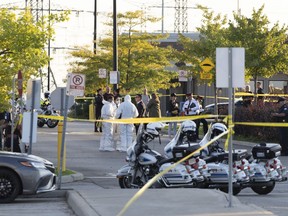 Police vehicles and officers are seen behind tape at a scene in Mississauga, Ont., Monday, Sept. 12, 2022. A Toronto police officer has been fatally shot and a suspect is dead after shooting scenes spanning three Greater Toronto Area cities Monday afternoon, left a third person dead and three others injured.