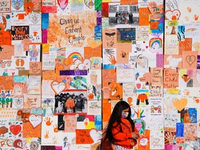 A child stands by a wall of "Every Child Matters," artwork during the National Day for Truth and Reconciliation in Ottawa on Thursday, Sept. 30, 2021.