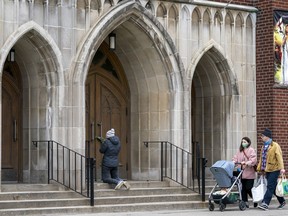 A woman prays on the steps outside St. Casimir Church in Toronto on Friday May 1, 2020.
