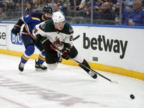 Arizona Coyotes' Barrett Hayton (29) reaches for a loose puck as St. Louis Blues' Nick Leddy (4) watches during the third period of an NHL hockey game Monday, April 4, 2022, in St. Louis.