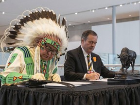 Elder Leonard Bastien, left, and Alberta Premier Jason Kenney, sign a co-stewardship agreement as they announce a new path forward regarding the stewardship of Manitou Asiniy or Manitou Stone, in Edmonton, on Friday, Sept. 30, 2022.