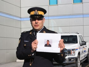 RCMP Sgt. Chris Manseau holds up a photo of Thaddeus McNeely outside of RCMP headquarters in Yellowknife, Thursday, Sept. 22, 2022. Police have identified McNeely, 24, as the lone suspect in a fatal stabbing in Fort Good Hope, N.W.T.