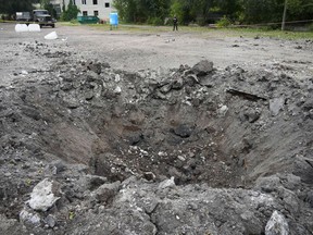 A police officer stands next to a crater created by an explosion after a Russian rocket attack in Zaporizhzhia, Ukraine, Friday, Sept. 30, 2022. A Russian strike on the Ukrainian city of Zaporizhzhia killed at least 23 people and wounded dozens, an official said Friday. Vladimir Putin's claim to parts of Ukraine is little more than "political theatre" with "no legitimacy," Canada and the United States declared Friday, and should have no impact on how best to deploy military aid from the West.