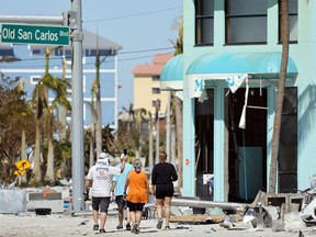 Island residents walk around the downtown area on the island of Fort Myers Beach, Fla., Friday, Sept. 30, 2022. Hurricane Ian made landfall Wednesday, Sept. 28, 2022, as a Category 4 hurricane on the southwest coast of Florida.