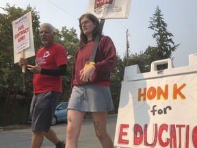 Guillermo Carvajal, a member of the support staff at Northgate Elementary School in Seattle, and Erin Carroll, an occupational therapist there, picket outside the building on the third day of a strike by the Seattle Education Association on Friday, Sept. 9, 2022. The union and Seattle Public Schools continued negotiating over issued that include pay and support for special needs students. It remained unclear how long the strike might last.
