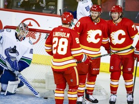 Vancouver Canucks goalie Collin Delia, left, clears the puck from the net as Calgary Flames forward Jonathan Huberdeau, centre right, celebrates his goal with teammates forward Elias Lindholm and forward Tyler Toffoli, right, during second period NHL pre-season hockey action in Calgary, Alta., Sunday, Sept. 25, 2022.