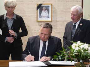 Quebec Premier Francois Legault signs the condolence book dedicated to Queen Elizabeth II witnessed by Lieutenant Governor of Quebec, Michel Doyon and wife Isabelle Brais in Quebec City, Friday, Sept. 9, 2022.
