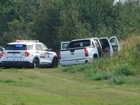 Police and investigators are seen at the side of the road outside Rosthern, Sask., on Wednesday, Sept. 7, 2022. In late spring, a parole officer issued an arrest warrant for Myles Sanderson, a Saskatchewan man with a violent past who had recently been released from prison.