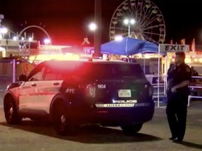 This image made from video provided by KVII shows a police officer stands beside a police car near a shooting scene in Amarillo, Texas Monday, Sept. 19, 2022. A gunman shot a few people, including first responders, at the Tri-State Fair & Rodeo in Texas, before he was shot and wounded by sheriff's deputies, authorities said.(KVII via AP)