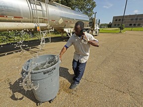 Santonia Matthews, a custodian at Forest Hill High School in Jackson, Miss., hauls away a trash can filled with water from a tanker in the school's parking lot, Wednesday, Aug. 31, 2022. The tanker is one of two placed strategically in the city to provide residents non-potable water. The recent flood worsened Jackson's longstanding water system problems and the state Health Department has had Mississippi's capital city under a boil-water notice since late July.