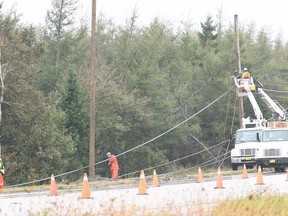 Nova Scotia Power crews work to repair toppled power lines in front of the entrance to the McCurdy Airport in Sydney, N.S., Monday, Sept. 26, 2022.