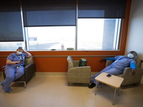 Respiratory therapist Alisha Clark, left, and registered nurse Joy Turner take a rest in the employee break room in the intensive care unit at the Humber River Hospital during the COVID-19 pandemic in Toronto on Tuesday, January 25, 2022. Groups representing thousands of public sector workers are taking the Ontario government to court over a law that caps wages.THE CANADIAN PRESS/Nathan Denette