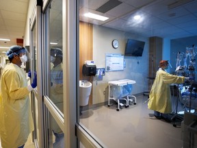 A heath-care worker watches through protective glass as one of his colleagues attends to a COVID-19 patient on a ventilator in the intensive care unit at the Humber River Hospital during the COVID-19 pandemic in Toronto on Tuesday, January 25, 2022.&ampnbsp;Members of Ontario's outgoing science table say they weren't consulted on the province's new COVID-19 strategy that dropped isolation rules.
