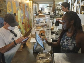 Kymme Williams-Davis, right, takes orders at the Bushwick Grind Café she owns, Thursday Sept. 8, 2022, in New York. Williams-Davis has noticed a definite shift in customer demand since she's had to raise prices and switch to different types of goods to keep up with inflation.
