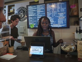 Kymme Williams-Davis, right, takes an order at theBushwick Grind Café she owns, while barista Derek Deyling creates a beverage, Thursday Sept. 8, 2022, in New York.