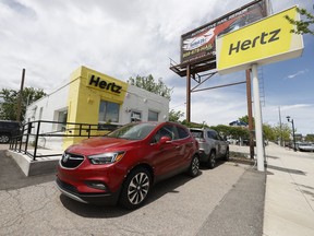 This May 23, 2020, photo shows rental vehicles parked outside a closed Hertz car rental office in south Denver. Rental car company Hertz plans to order up to 175,000 Chevrolet, Buick, GMC, Cadillac and BrightDrop electric vehicles from General Motors over the next five years. The deal includes electric vehicle deliveries through 2027 and will span a variety of vehicles such as SUVs, pickups and luxury automobiles.
