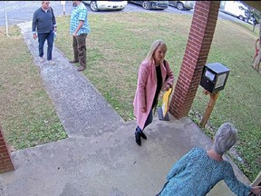 FILE - In this image taken from Coffee County, Ga., security video, Cathy Latham, bottom, chair of the Coffee County Republican Party, greets a team of computer experts from data solutions company SullivanStrickler at the county elections office in Douglas, Ga., on Jan. 7, 2021. Lawyers investigating a breach of voting system data that potentially has put Georgia's election system at risk are asking a judge to order former Republican Party chair Latham to turn over data from her personal devices, which they say could help determine what happened to the breached data and who orchestrated the scheme. (Coffee County via AP, File)