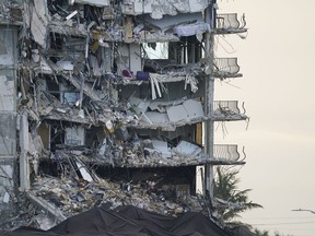 FILE - A giant tarp, bottom, covers a section of rubble where search and rescue personnel have been working at the Champlain Towers South condo building in Surfside, Fla., on July 4, 2021. Lawyers who secured a $1.1 billion settlement in the deadly collapse last year of the beachfront Florida condominium building were awarded more than $70 million in fees Monday, Aug. 29, 2022 by a judge.