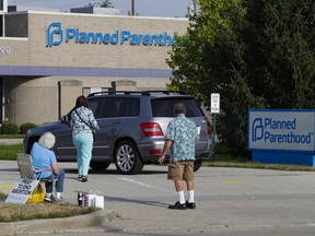 FILE - Abortion protesters attempt to hand out literature as they stand in the driveway of a Planned Parenthood clinic in Indianapolis, Aug. 16, 2019. Hospitals and abortion clinics in Indiana are preparing for the state's abortion ban to go into effect on Sept. 15, 2022. Starting Sept. 15, abortions will be permitted only in cases of rape and incest, before 10-weeks post-fertilization; to protect the life and physical health of the patient; and if a fetus is diagnosed with a lethal anomaly. The law also prohibits abortion clinics from providing any abortion care.