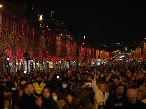 FILE - Spectators gather to attend the Champs Elysee Avenue illumination ceremony for the Christmas season, in Paris, Sunday, Nov. 21, 2021. The committee governing Paris' Champs-Elysees says Tuesday Sept.20, 2022 they are switching off the lights on the famed avenue at the earlier time of 10pm from now and and until further notice to help save energy -- as the war in Ukraine squeezes the electricity market.