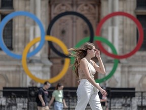FILE - A woman passes by the Olympic rings at the City Hall in Paris, Monday, July 25, 2022. Paris Olympic organizers appointed prize-winning French theater director Thomas Jolly on Wednesday Sept. 21, 2022 to direct the opening and closing ceremonies of the 2024 Games and Paralympics.