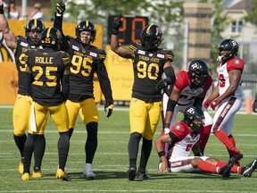 Hamilton Tiger Cats defensive tackle Dylan Wynn (98), left, celebrates with teammates after sacking Ottawa Redblacks quarterback Caleb Evans (5), right, during first half CFL football game action in Hamilton, Ont., Saturday, July 16, 2022. The defensive formations and schemes in pro football are detailed and complicated but the ultimate goal for Wynn has never wavered.