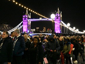 People queue to pay their respects as the Tower Bridge is lit up in purple to honour Queen Elizabeth II, following her death, in London, England September 16, 2022.