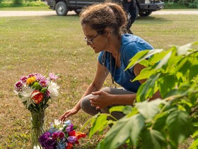 Ruby Works places flowers at the home of a victim who has been identified by residents as Wes Petterson in Weldon, Sask., on Monday, September 5, 2022. Works said that the 77-years-old victim was like an uncle to her. Saskatchewan RCMP say arrest warrants have been issued for two suspects in a deadly stabbing rampage who remain at large.