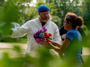 Ruby Works spricht mit einem forensischen Ermittler, bevor er am Montag, den 5. September 2022 Blumen zum Haus eines Opfers bringt, das von Anwohnern als Wes Petterson in Weldon, Sask., identifiziert wurde.