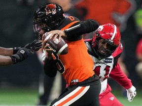 B.C. Lions quarterback Vernon Adams Jr. (8) is grabbed by Calgary Stampeders' Mike Rose, back right, during the first half of CFL football game in Vancouver, on September 24, 2022. While his first three games with the B.C. Lions have had ups and downs, the quarterback hasn't thrown a touchdown yet.