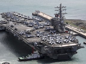FILE - The aircraft carrier USS Ronald Reagan (CVN 76) is escorted into Busan port, South Korea, after completing a joint drill with the South Korean military on Oct. 21, 2017. A U.S. aircraft carrier is to visit South Korea this week for its first joint training with South Korean warships in five years, officials said Monday, Sept. 19, 2022, in an apparent show of force against increasing North Korean nuclear threats.