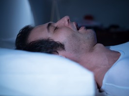 Man is sleeping in his bed at night with sleep apnea