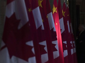 A Chinese flag, flanked by Canadian flags, is illuminated by sunshine in the Hall of Honour on Parliament Hill in Ottawa, on Sept. 22, 2016.