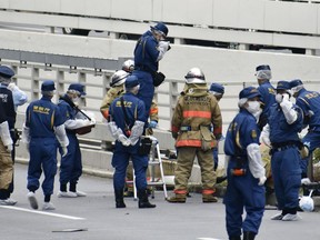 Police and firefighters inspect the scene where a man is reported to set himself on fire, near the Prime Minister's Office in Tokyo, Wednesday, Sept. 21, 2022. The man was taken to a hospital Wednesday, in an apparent protest against a planned state funeral next week for the assassinated former leader Shinzo Abe, officials and media reports said.