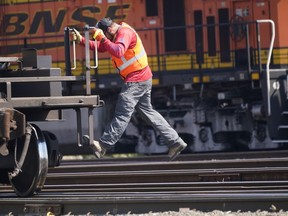 A worker rides a rail car at a BNSF rail crossing in Saginaw, Texas, Wednesday, Sept. 14, 2022. Business and government officials are preparing for a potential nationwide rail strike at the end of this week while talks carry on between the largest U.S. freight railroads and their unions.