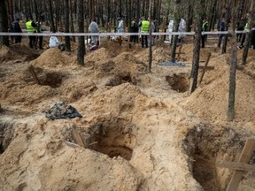 Police and experts work at a place of mass burial during an exhumation in the town of Izium, recently liberated by Ukrainian Armed Forces, in Kharkiv region, Ukraine Sept. 17, 2022.