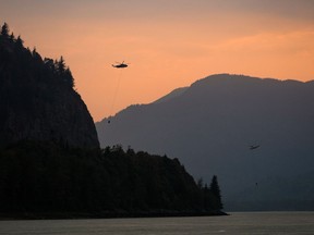 Helicopters with water buckets battling the Flood Falls Trail wildfire pick up water from the Fraser River, in Hope, B.C., Monday, Sept. 12, 2022.