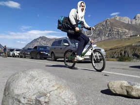 A Russian man rides a bicycle towards the border crossing at Verkhny Lars between Georgia and Russia leaving Chmi, North Ossetia - Alania Republic, Russia, Thursday, Sept. 29, 2022. Long lines of vehicles have formed at a border crossing between Russia's North Ossetia region and Georgia after Moscow announced a partial military mobilization. A day after President Vladimir Putin ordered a partial mobilization to bolster his troops in Ukraine, many Russians are leaving their homes. (AP Photo)