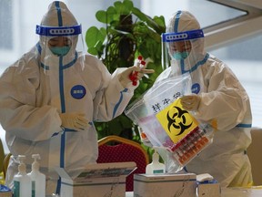 FILE - Health workers wearing protective suits put COVID-19 test samples into a bag at a hotel used for people to stay during a period of health quarantine on March 20, 2022, in the Yanqing district of Beijing. China on Friday, Sept. 30, 2022 dismissed complaints from two U.S. congressmembers over the quarantining of American diplomats and their family members under the country's strict COVID-19 regulations.