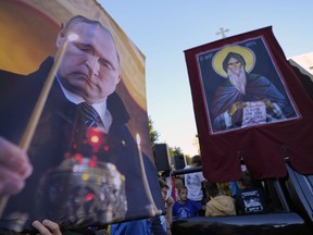 People hold icons and a picture of Russian President Vladimir Putin during a protest against the international LGBT event Euro Pride in Belgrade, Serbia, Sunday, Sept. 11, 2022. Thousands of opponents of a pan-European LGBTQ event planned for this week in Belgrade marched through the Serbian capital on Sunday despite an announced ban of Europe's largest annual gay gathering.