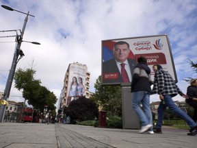 People walk past a pre-election billboard showing Bosnian Serb leader Milorad Dodik in Belgrade, Serbia, Thursday, Sept. 22, 2022. Bosnia has a general election on Oct. 2, in which Dodik is running for the Bosnian Serb presidency.