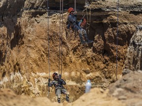Rescuers from the Guatemalan Army descend into a sinkhole in Villa Nueva, Guatemala, Tuesday, Sept. 27, 2022. Search efforts continue for a mother and daughter who disappeared when their vehicle was swallowed by the massive sinkhole.
