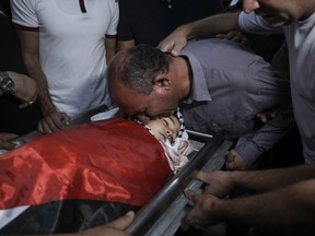 Father of 7-year-old Palestinian boy Rayan Suleiman, kisses his body at a hospital in the West Bank village of Beit Jala just before his funeral Friday, Sept. 30, 2022. The U.S. State Department has called on Israel to open a "thorough" investigation into the mysterious death of the boy, who collapsed and died shortly after Israeli soldiers came to his home in the occupied West Bank. Relatives said he had no previous health problems and accused the army of scaring the child to death. The army called the death a tragedy and said its soldiers were not to blame.