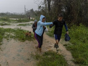 A family walks through the rain in search of shelter after their home flooded when Hurricane Ian hit in Pinar del Rio, Cuba, Tuesday, Sept. 27, 2022. Ian made landfall at 4:30 a.m. EDT Tuesday in Cuba's Pinar del Rio province, where officials set up shelters, evacuated people, rushed in emergency personnel and took steps to protect crops in the nation's main tobacco-growing region.