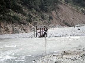 People cross a river on a suspended cradle, in Kalam Valley in northern Pakistan, Friday, Sept. 9, 2022. Guterres appealed to the world for help for cash-strapped Pakistan after arriving in the country Friday to see the climate-induced devastation from months of deadly record floods.