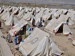 Victims of heavy flooding from monsoon rains stand beside their tents at a relief camp in Dasht near Quetta, Pakistan, Friday, Sept. 16, 2022. The government has more than doubled their cost-match of donations to help the people of Pakistan recover from disastrous flooding.