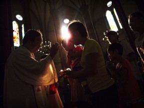 A Chinese Catholic woman takes communion from a priest during a service for the Assumption of the Virgin Mary at a government-sanctioned church in Beijing in 2014.